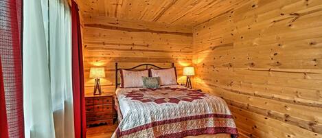 A wooden-paneled room with a bed, two bedside lamps, and a nightstand.