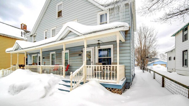 A two-story house with a covered porch and a snow-covered front yard. - Charming Negaunee Home ~ 2 Mi to Teal Lake! (Negaunee)