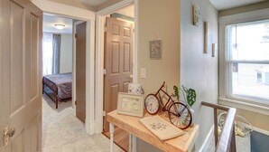 A hallway with a bed, a table with a bicycle, and a door leading to another room. - Charming Negaunee Home ~ 2 Mi to Teal Lake! (Negaunee)