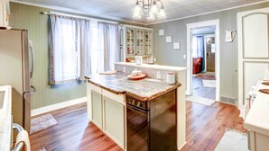 A kitchen with a central island, wooden flooring, and a built-in dishwasher. - Charming Negaunee Home ~ 2 Mi to Teal Lake! (Negaunee)