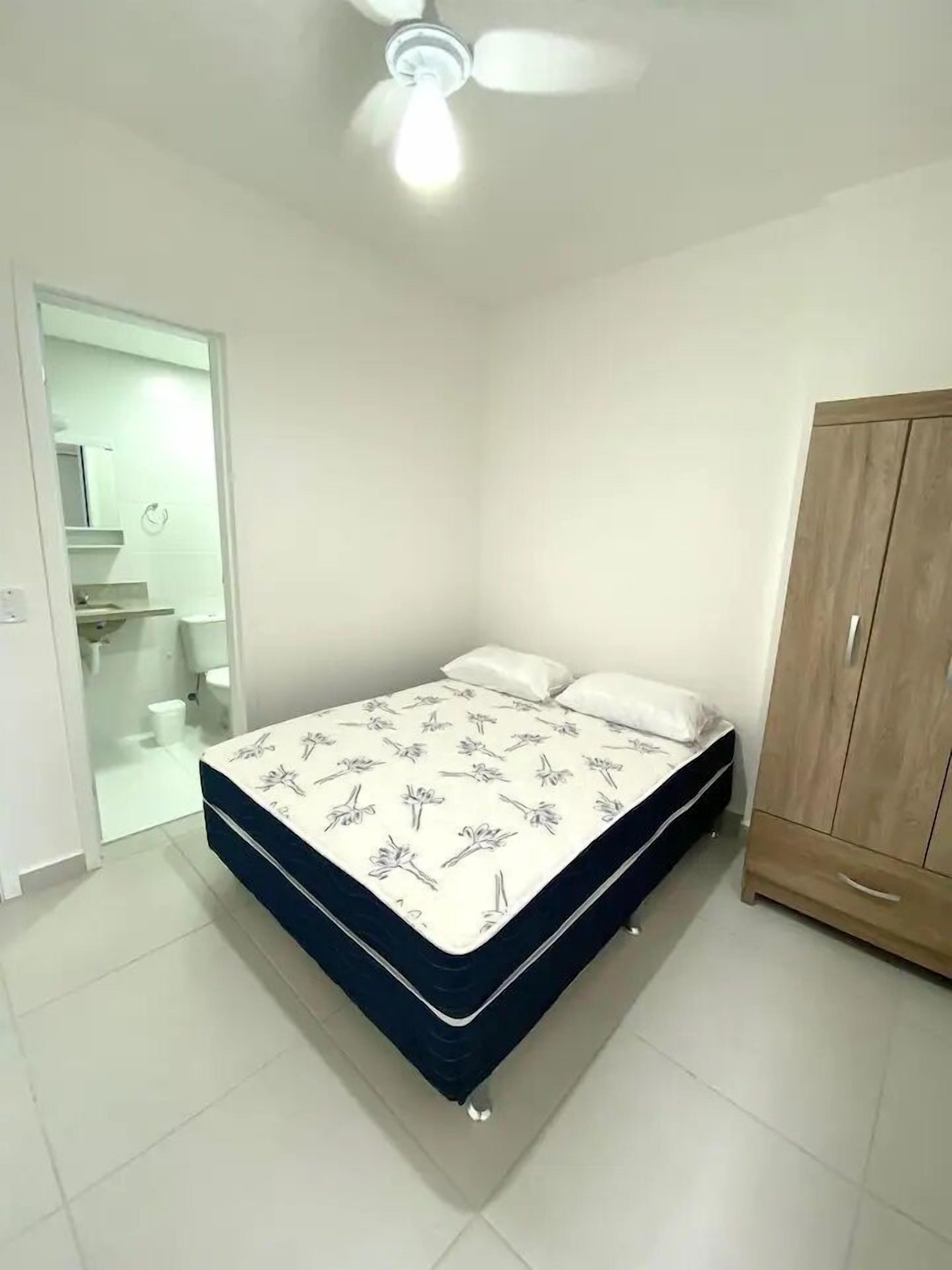 A bedroom with a bed, a wardrobe, and a ceiling fan.