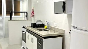 Une cuisine moderne avec des armoires blanches, un évier en acier inoxydable et un four encastré.