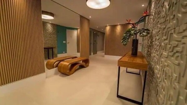 A modern interior with a wooden bench, a small table with a plant, and a textured wall.