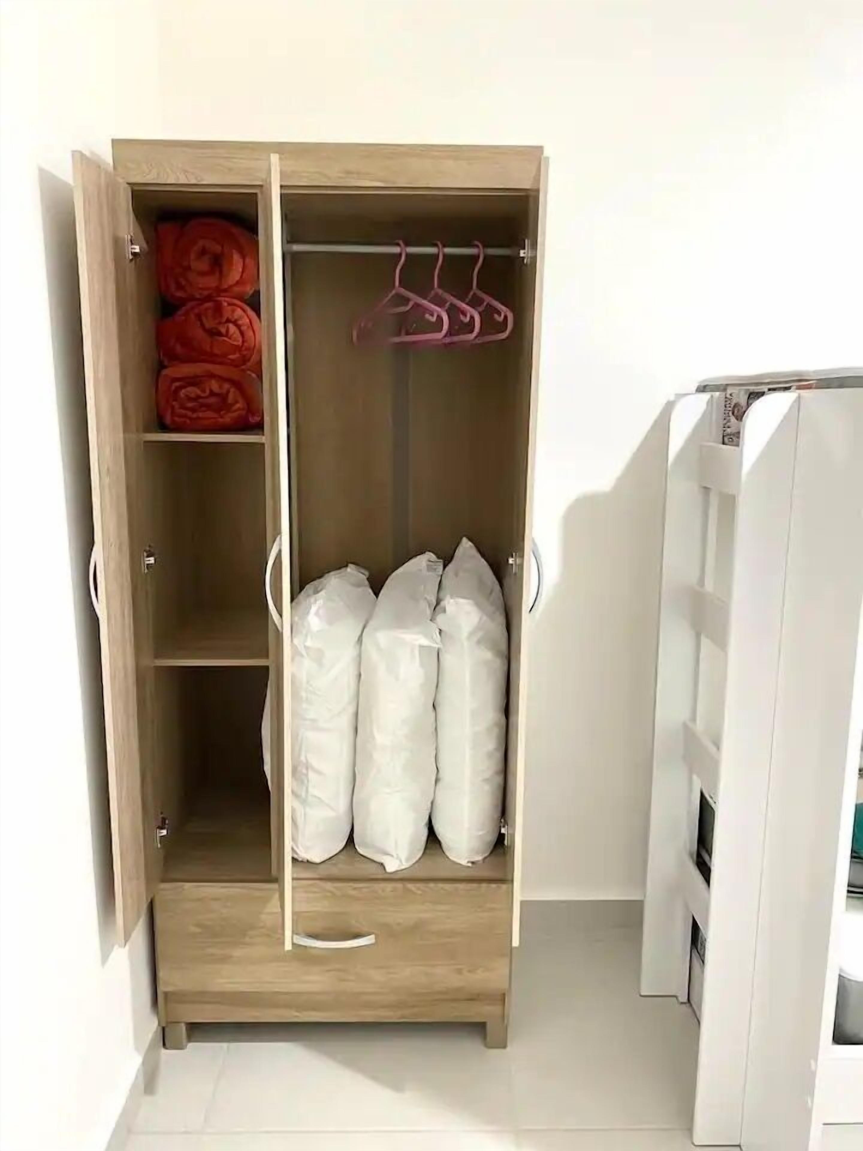 Puisesta vaatekaapista löytyy henkaritanko ja hyllyjä, ja siellä on rullalle taiteltuja pyyhkeitä ja tyynyjä.
