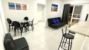 Un salon moderne comprenant un coin repas, un canapé avec des coussins bleus et un bar.