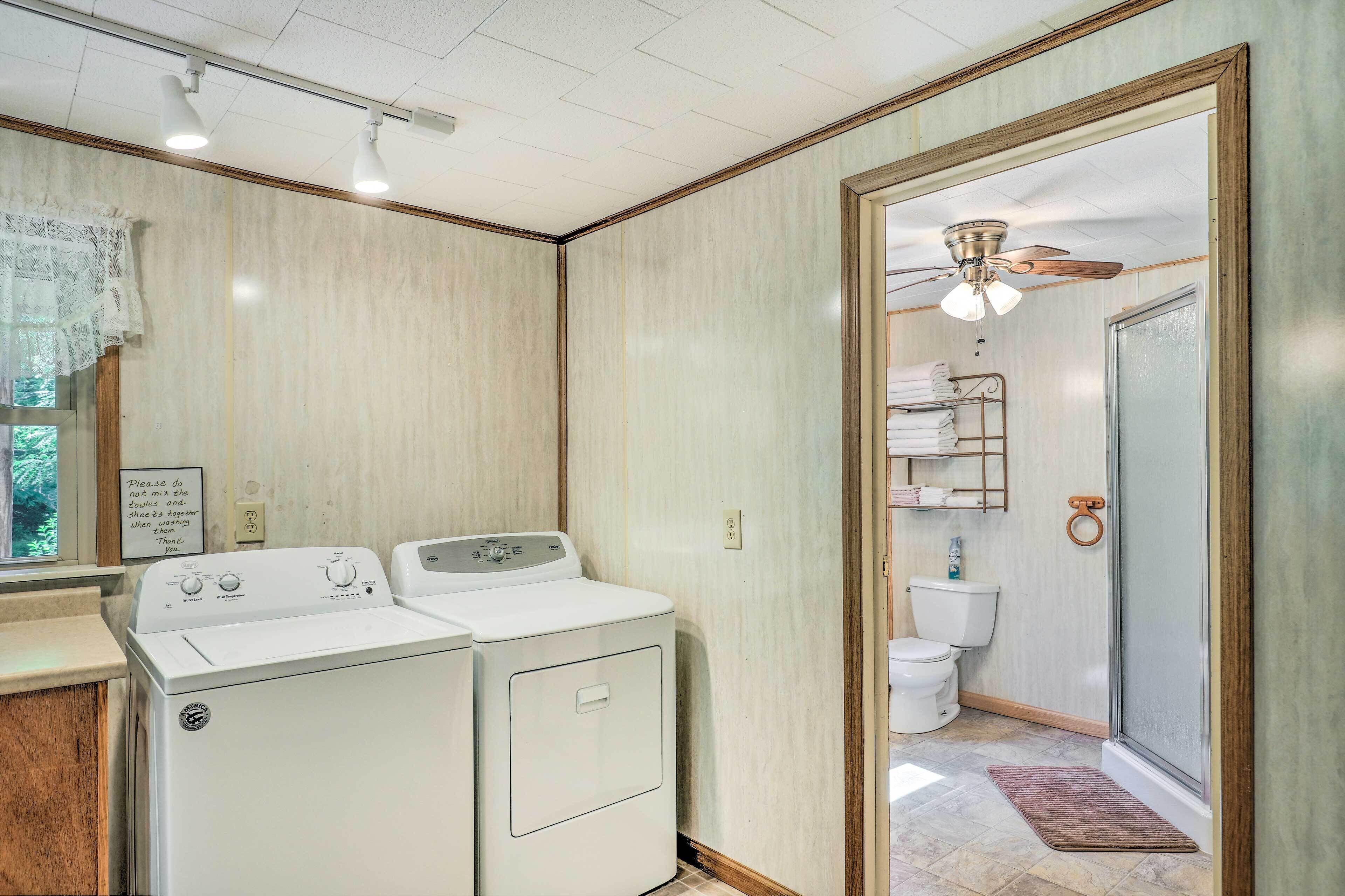 A laundry area with two washing machines, a shower with a glass door, and a toilet.