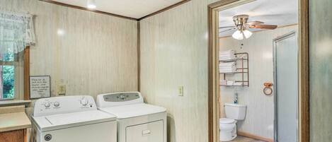 A laundry area with two washing machines, a shower with a glass door, and a toilet.