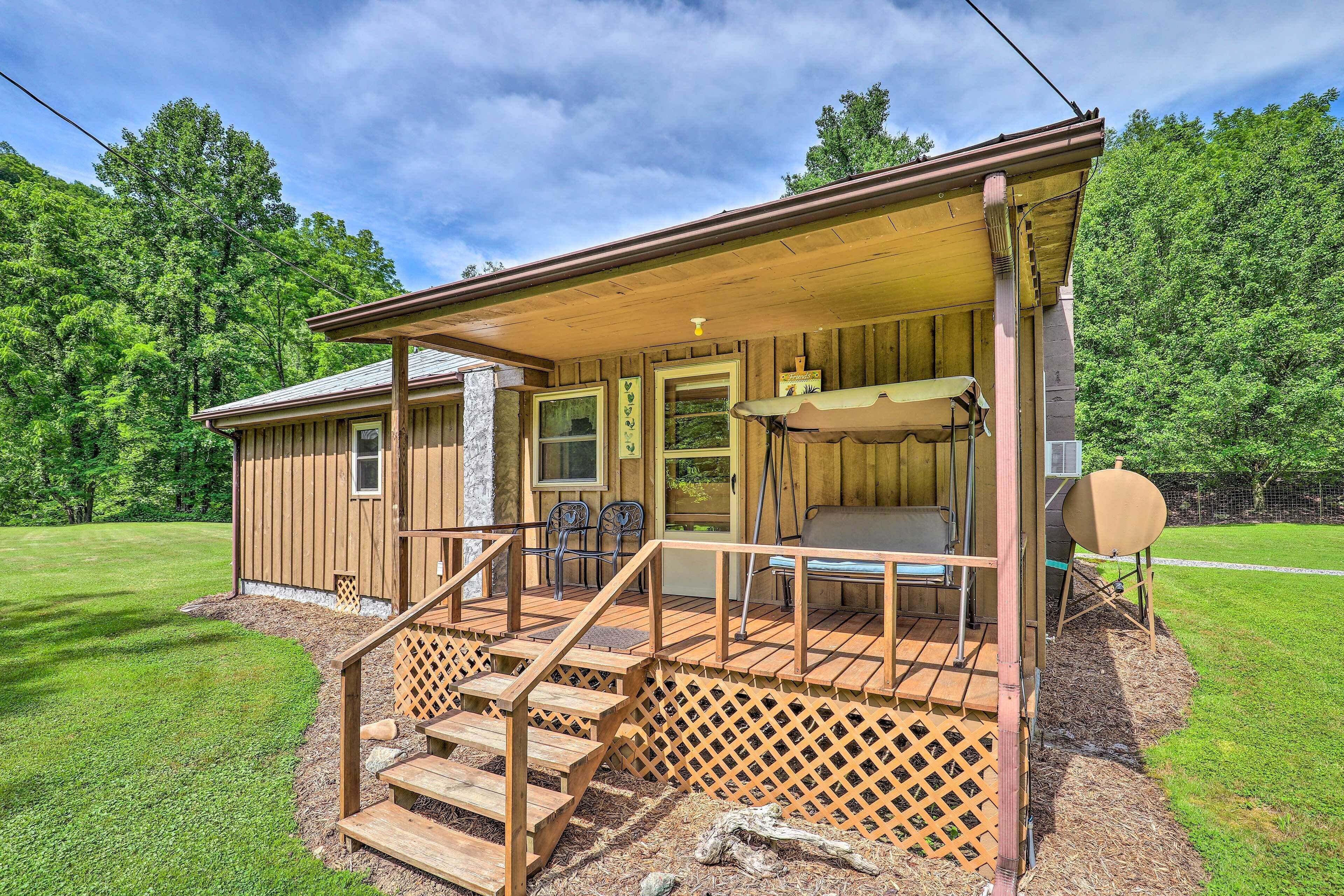 A wooden cabin with a porch, outdoor seating, and a grill area.