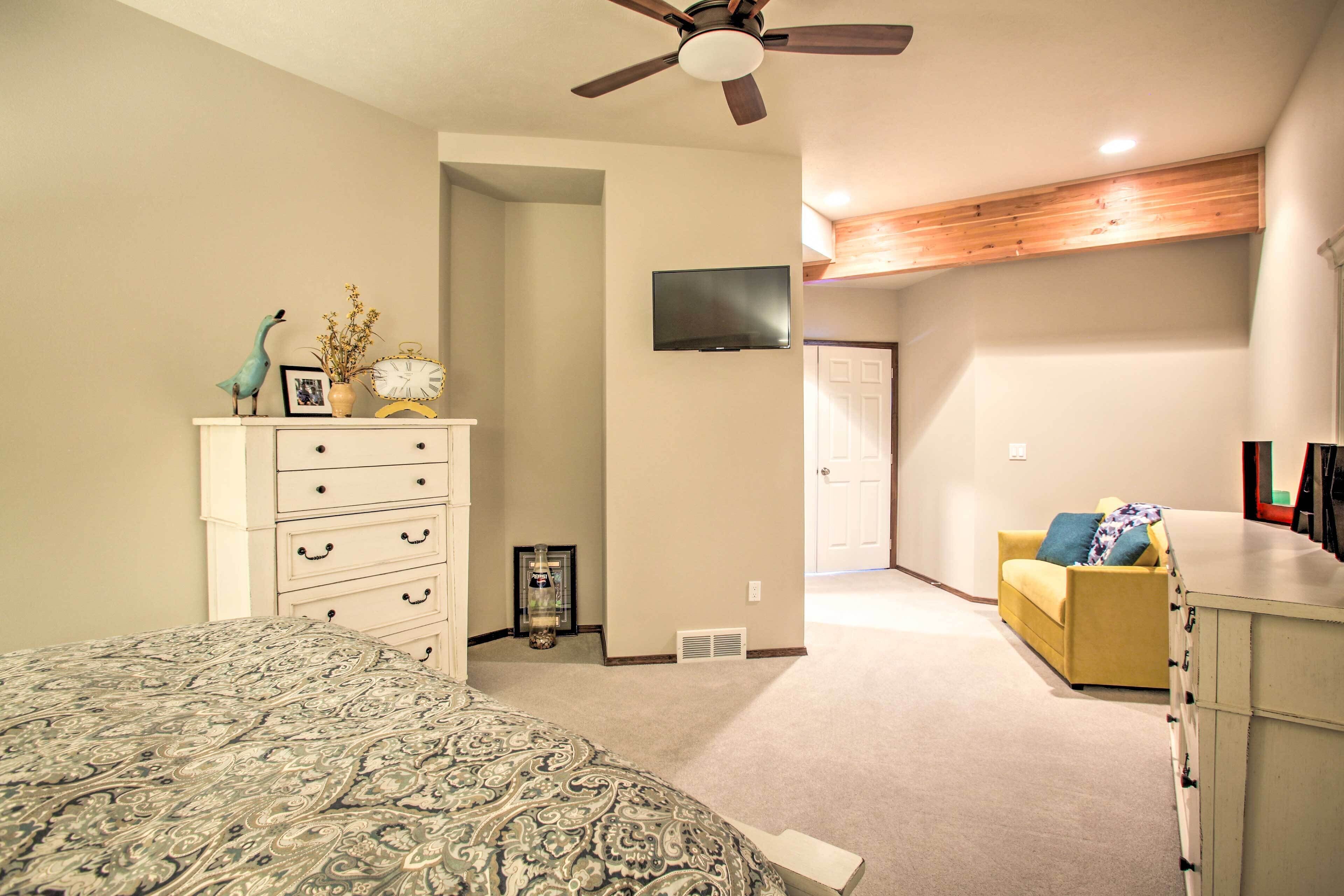 A bedroom with a bed, dresser, and a television mounted on the wall.