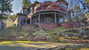 Una casa de varios pisos con terraza curva, muros de contención de piedra y un paisaje con césped.