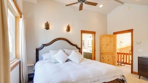 Un dormitorio con cama de madera, ventilador de techo y vista al deck exterior.