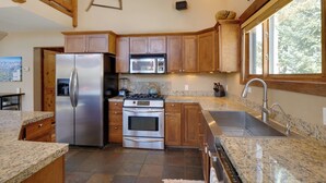 Una cocina moderna con electrodomésticos de acero inoxidable, armarios de madera, encimeras de granito y un amplio ventanal que proporciona luz natural.