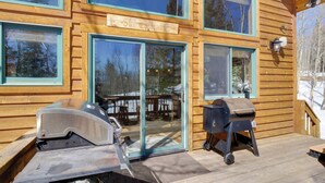 Una cabaña de madera con ventanas amplias, una parrilla y una mesa para asar.