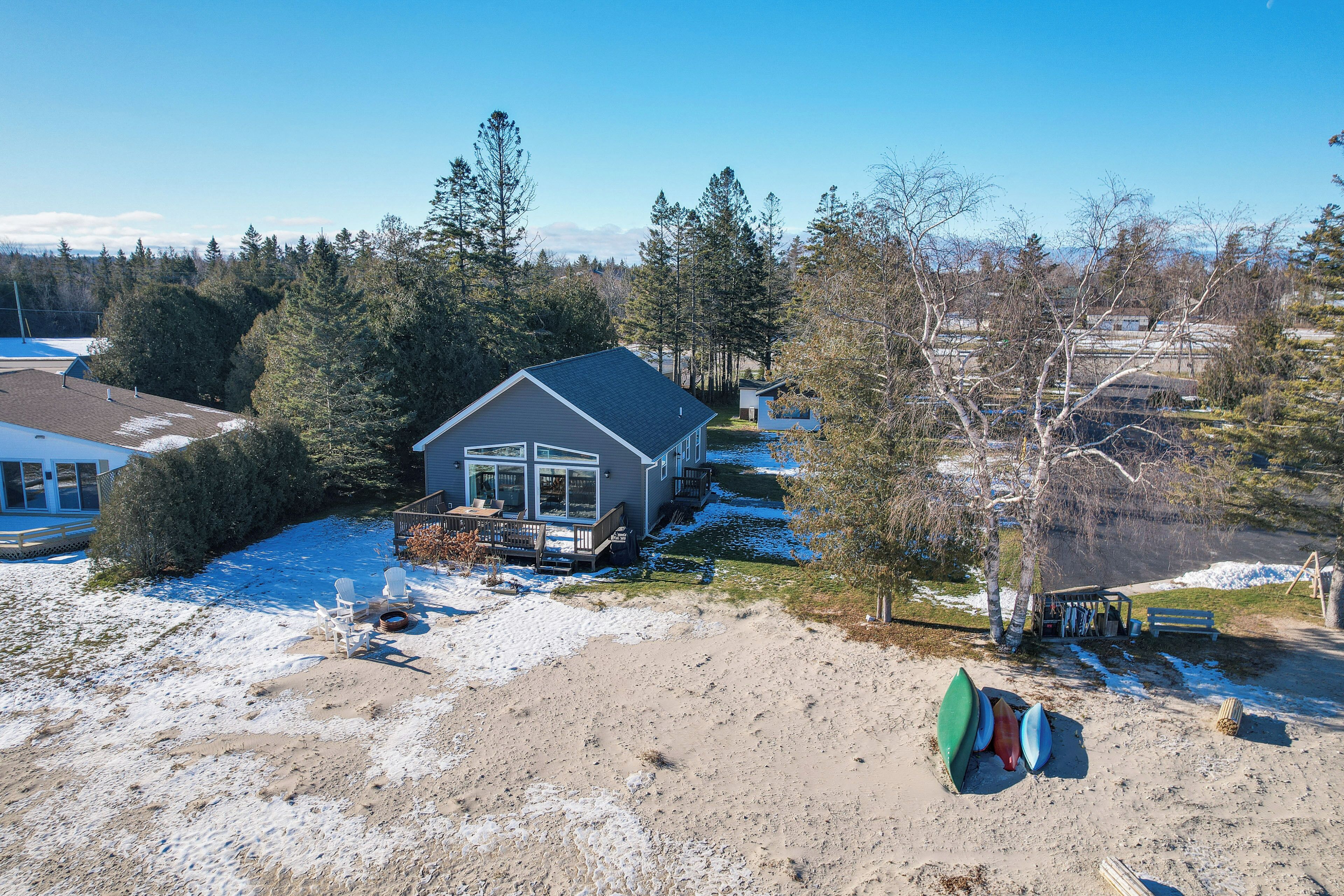 Ein Haus mit Veranda, umgeben von Bäumen und einem schneebedeckten Garten.