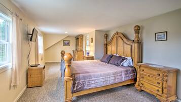 A bedroom with a wooden four-poster bed, a nightstand, a dresser, and a television mounted on the wall.