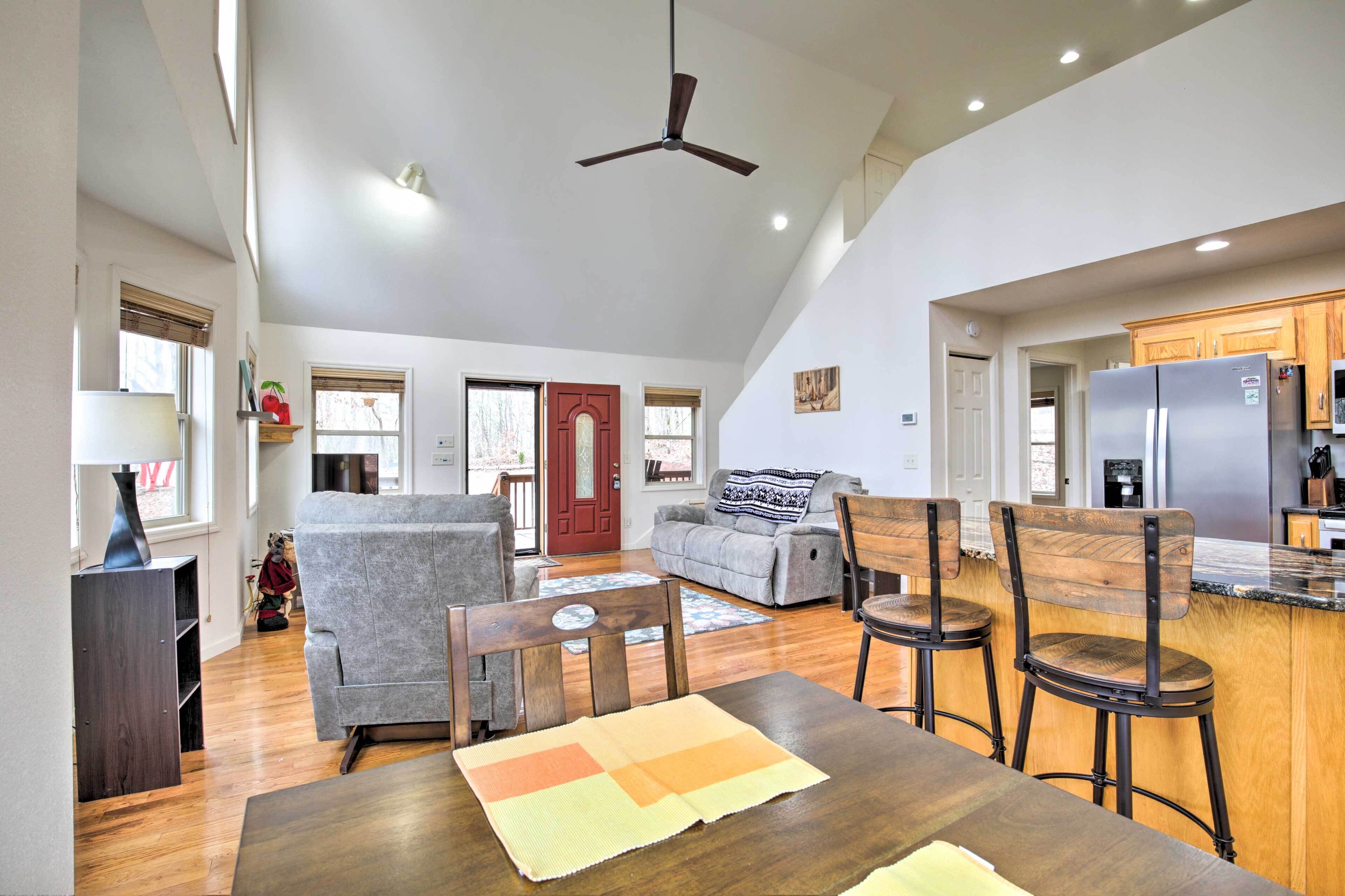 A spacious living area with a dining table, chairs, a sofa, and a kitchen with a refrigerator.