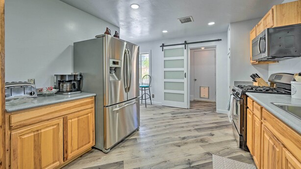 A modern kitchen with wooden cabinets, stainless steel appliances, and a herringbone wood floor. - Stylish Basecamp 6850' Near Downtown Williams! (Williams)