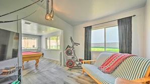 A living room with a pool table, exercise bike, and a sofa with a patterned throw. - Stylish Basecamp 6850' Near Downtown Williams! (Williams)