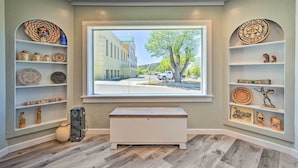 A room with a large window, wooden flooring, and shelves with decorative items. - Stylish Basecamp 6850' Near Downtown Williams! (Williams)
