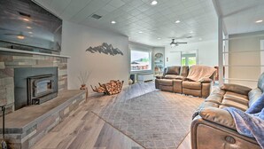 A modern living room with a fireplace, leather sofa, and a large window. - Stylish Basecamp 6850' Near Downtown Williams! (Williams)