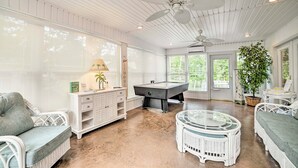 A spacious room with a pool table, wicker furniture, and a ceiling fan. - Kentucky Lake House With a Great Outdoor Space! (Gilbertsville)