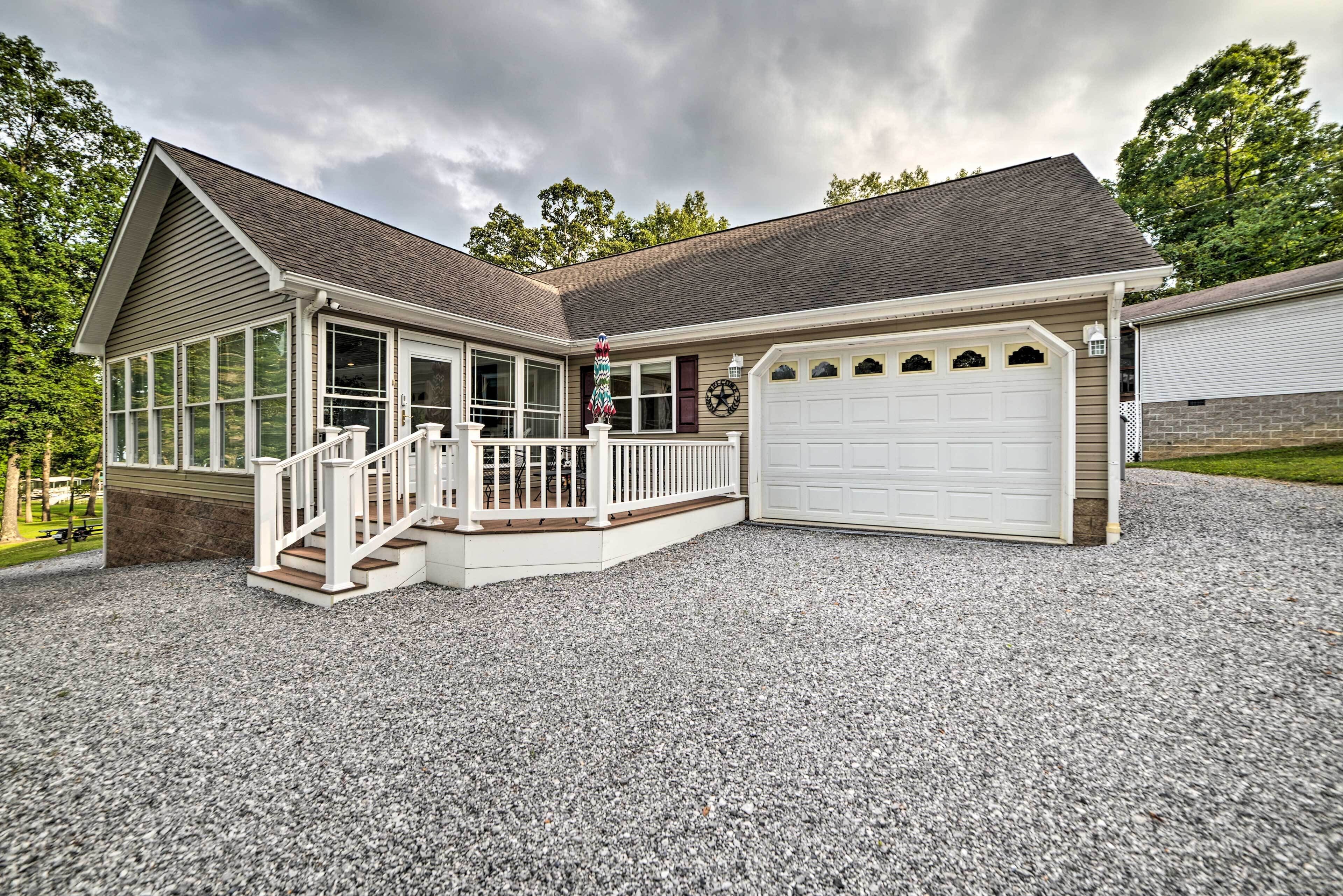 A two-story house with a covered porch, a garage, and a gravel driveway.