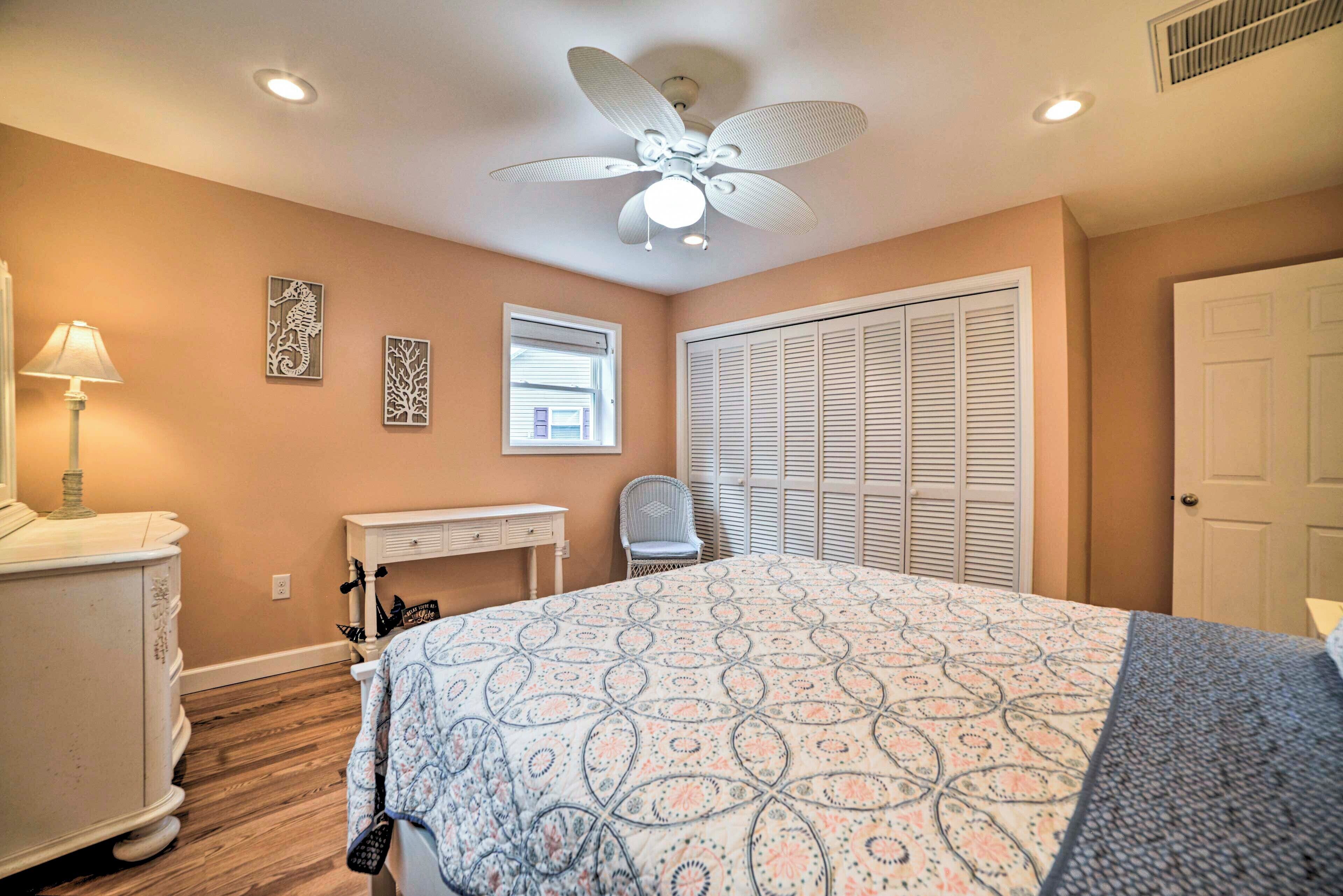 A bedroom with a bed, a desk, a chair, a wardrobe, and a ceiling fan.