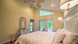 A bedroom with a large bed, a dresser, a mirror, and a ceiling fan. - Kentucky Lake House With a Great Outdoor Space! (Gilbertsville)