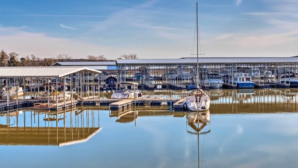 A marina with boats docked, a covered building, and a clear sky. - Kentucky Lake House With a Great Outdoor Space! (Gilbertsville)