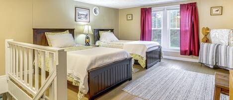 Une chambre avec deux lits, une fenêtre avec des rideaux, un plancher en bois et une rambarde blanche.