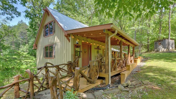 Un chalet rustique doté d’un porche en bois, niché au cœur d’une forêt naturelle.