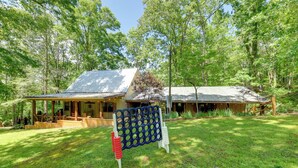 Un chalet rustique doté d’un porche abrité et d’une terrasse en bois, entouré d’une forêt luxuriante.
