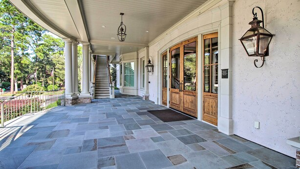 A covered porch with stone flooring, wooden doors, and wall-mounted lanterns. - Walk to Pier & Golf: Heart of Harbour Town Condo (Hilton Head Island)