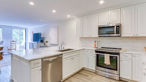 A modern kitchen with white cabinets, a stainless steel microwave, and an oven. - Walk to Pier & Golf: Heart of Harbour Town Condo (Hilton Head Island)