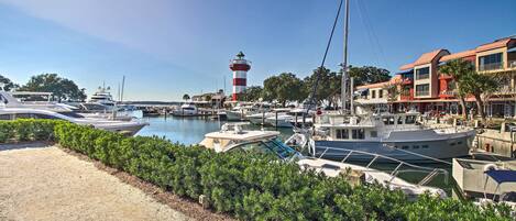 A marina with boats docked, a lighthouse, and a building with a red roof.
