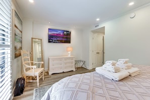 Ein Schlafzimmer mit einem Bett, einem Schminktisch, einem Sessel, einem Fernseher und einer Tür.