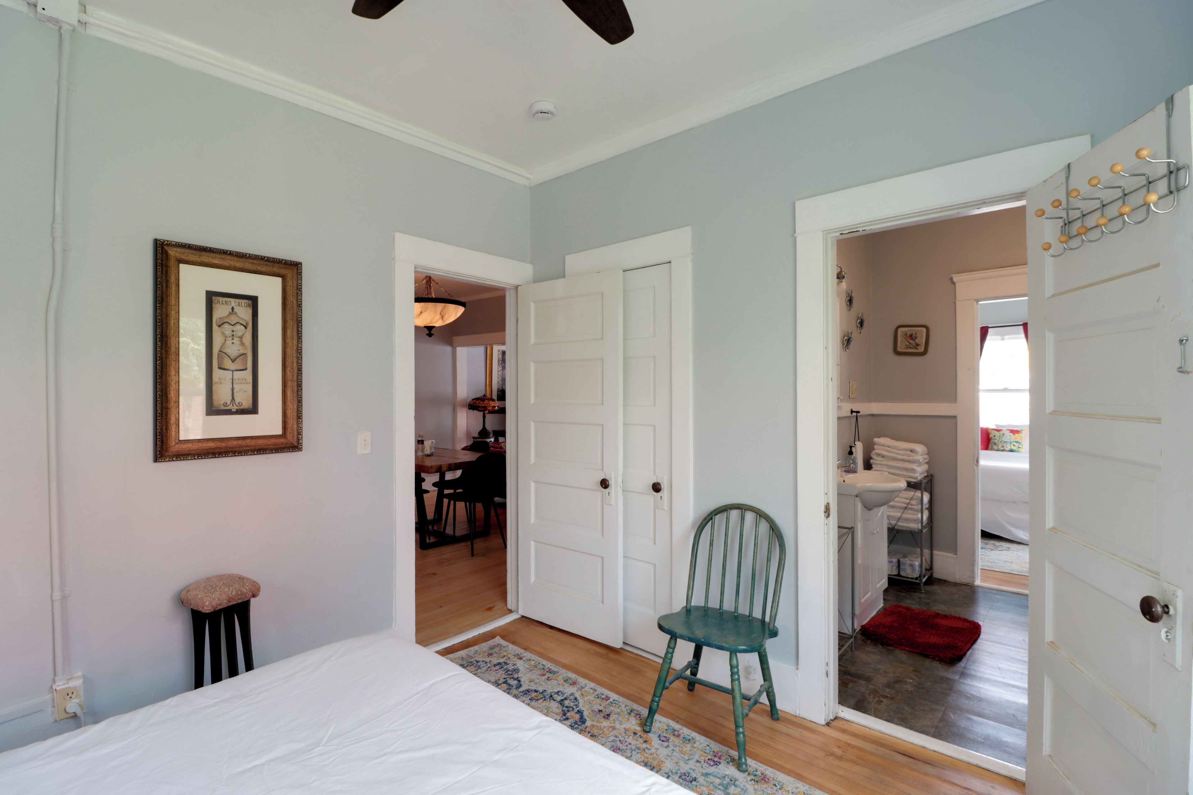 A bedroom with a bed, a chair, and a door leading to a bathroom.