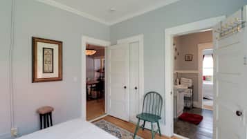 A bedroom with a bed, a chair, and a door leading to a bathroom.