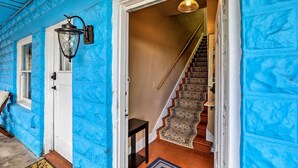 A staircase with a patterned carpet leading to a room with a white door and a wall-mounted light fixture.