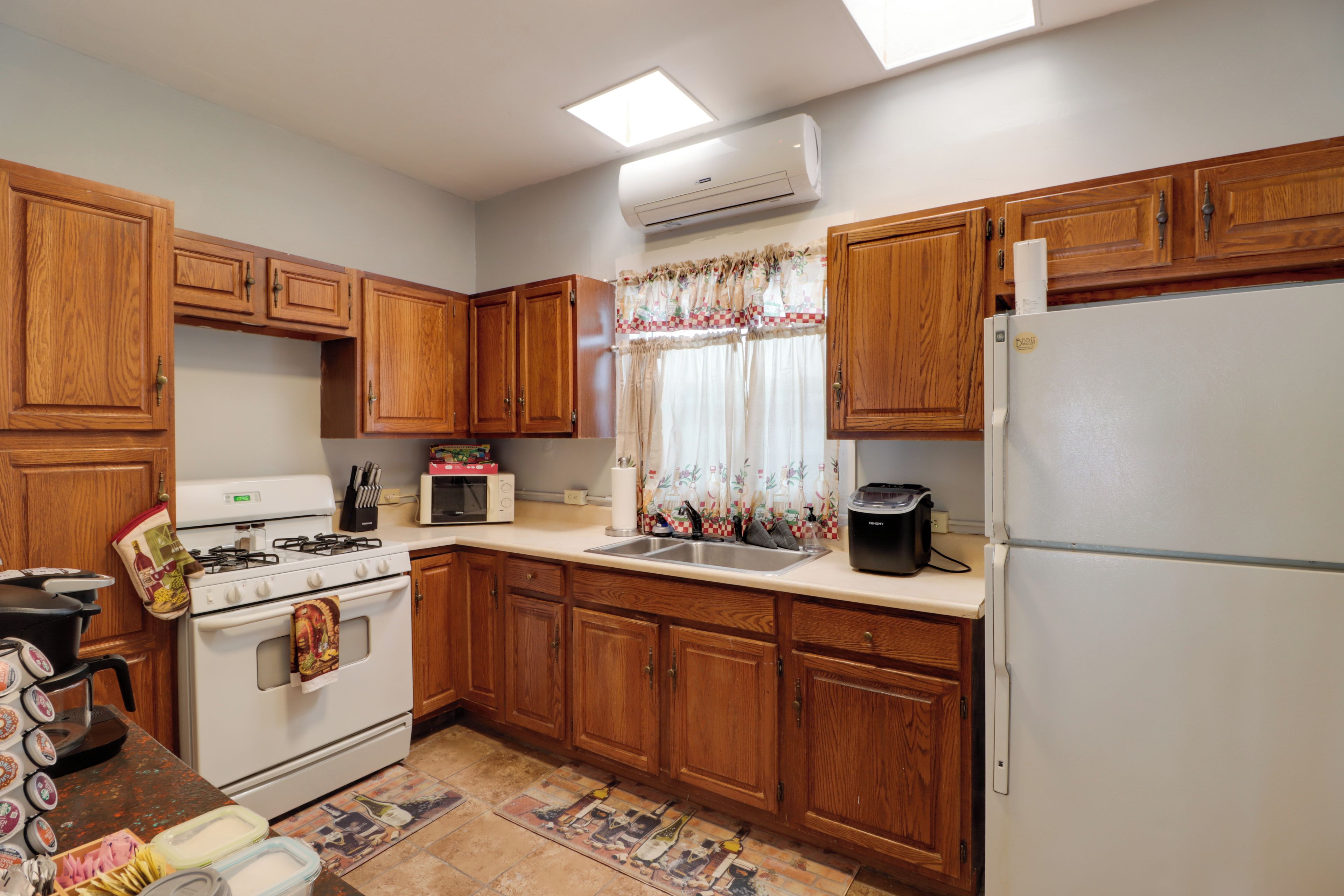 A kitchen with wooden cabinets, a stove, a microwave, a sink, and a refrigerator.