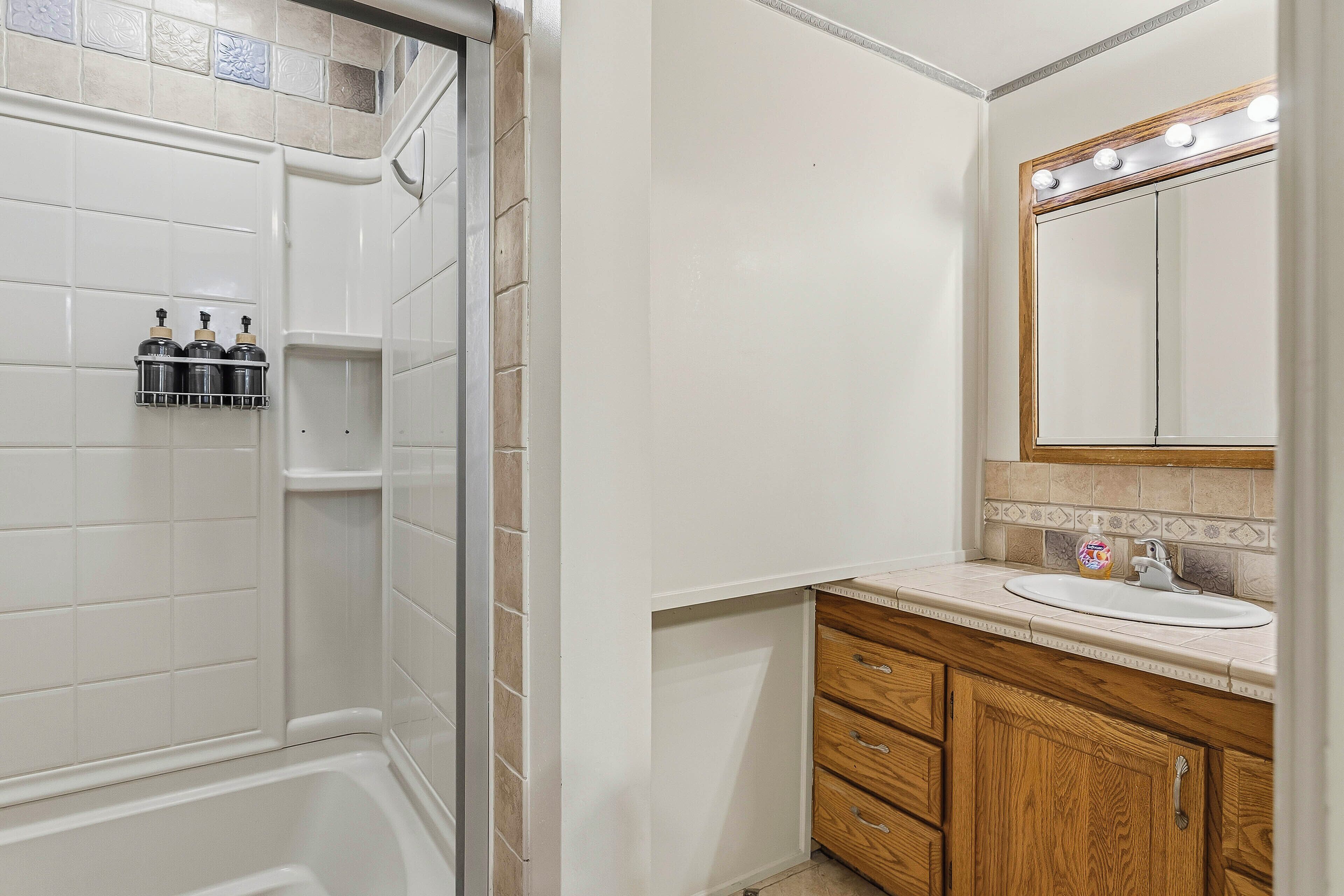 A bathroom with a shower, a sink, and wooden cabinets.