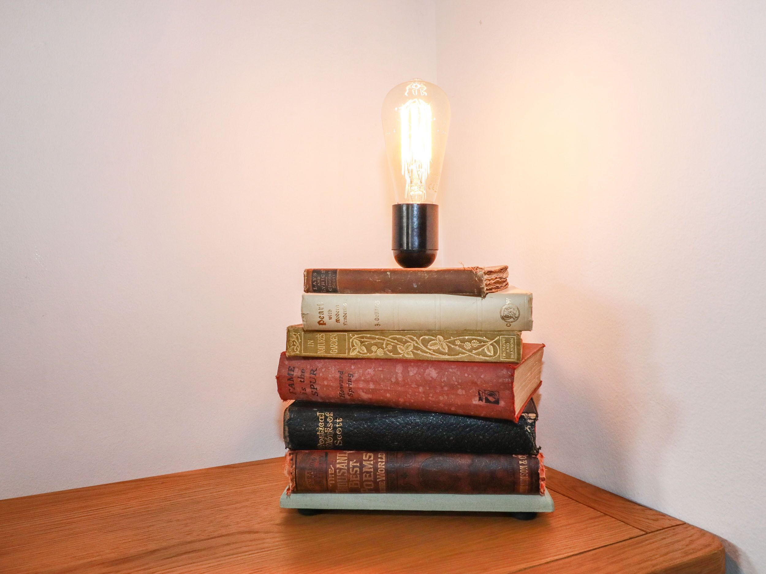 Una pila de libros con una bombilla encima, sobre una superficie de madera.