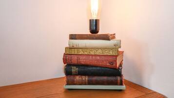 Una pila de libros con una bombilla encima, sobre una superficie de madera.