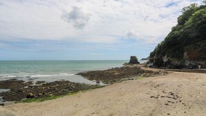 A beach with rocky shores, a clear sky, and a distant rocky formation.
