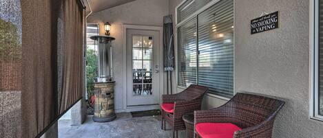 A covered porch with wicker chairs and a sign prohibiting smoking and vaping.