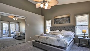 A bedroom with a large bed, a ceiling fan, a mirror, and a window with blinds. - Beautiful Backyard: Comfortable Phoenix Getaway! (Phoenix)