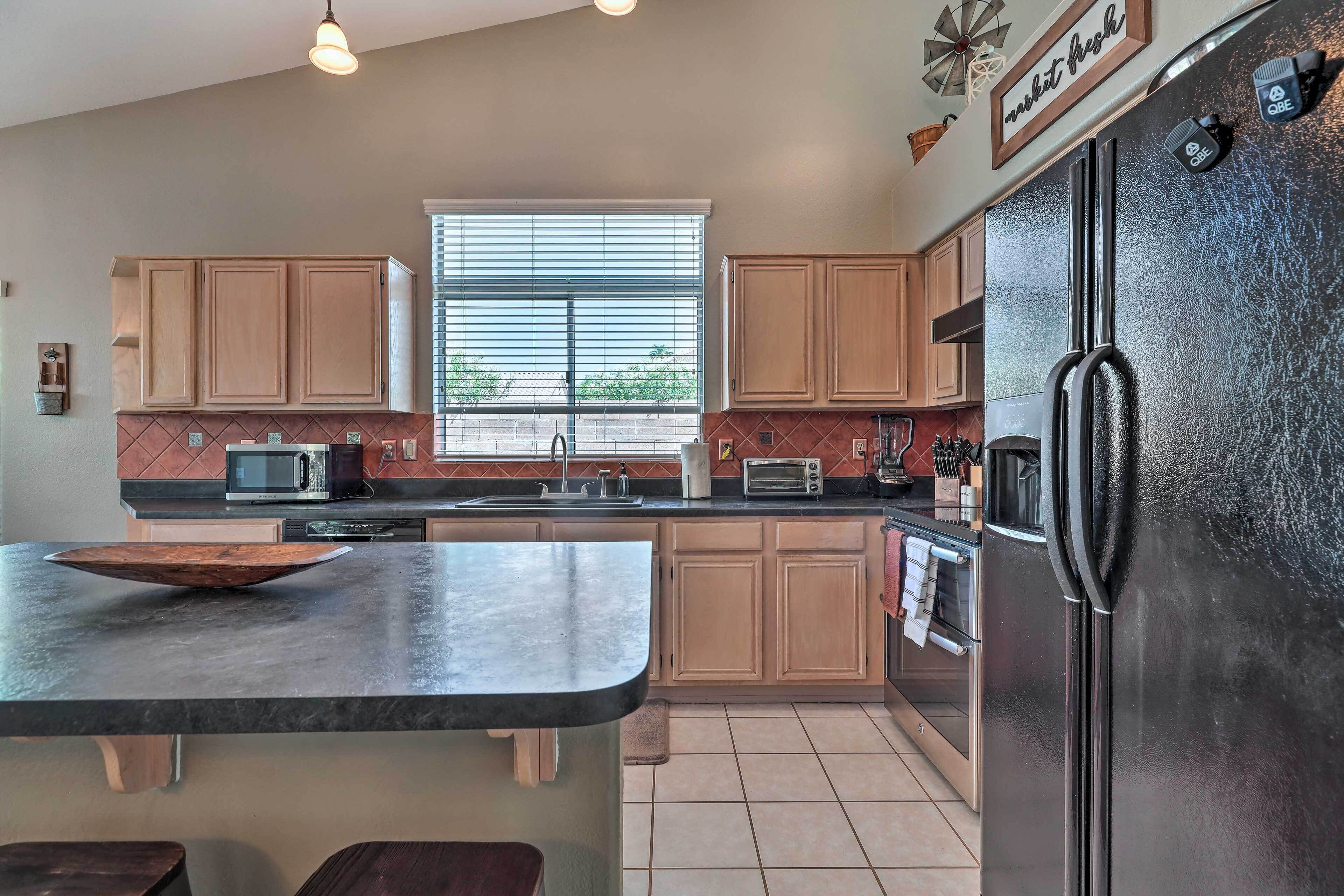 A modern kitchen with wooden cabinets, a black refrigerator, and a large window.