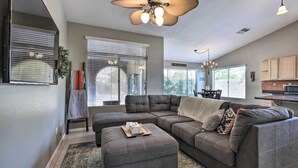 A modern living room with a sectional sofa, ottoman, and a ceiling fan. - Beautiful Backyard: Comfortable Phoenix Getaway! (Phoenix)
