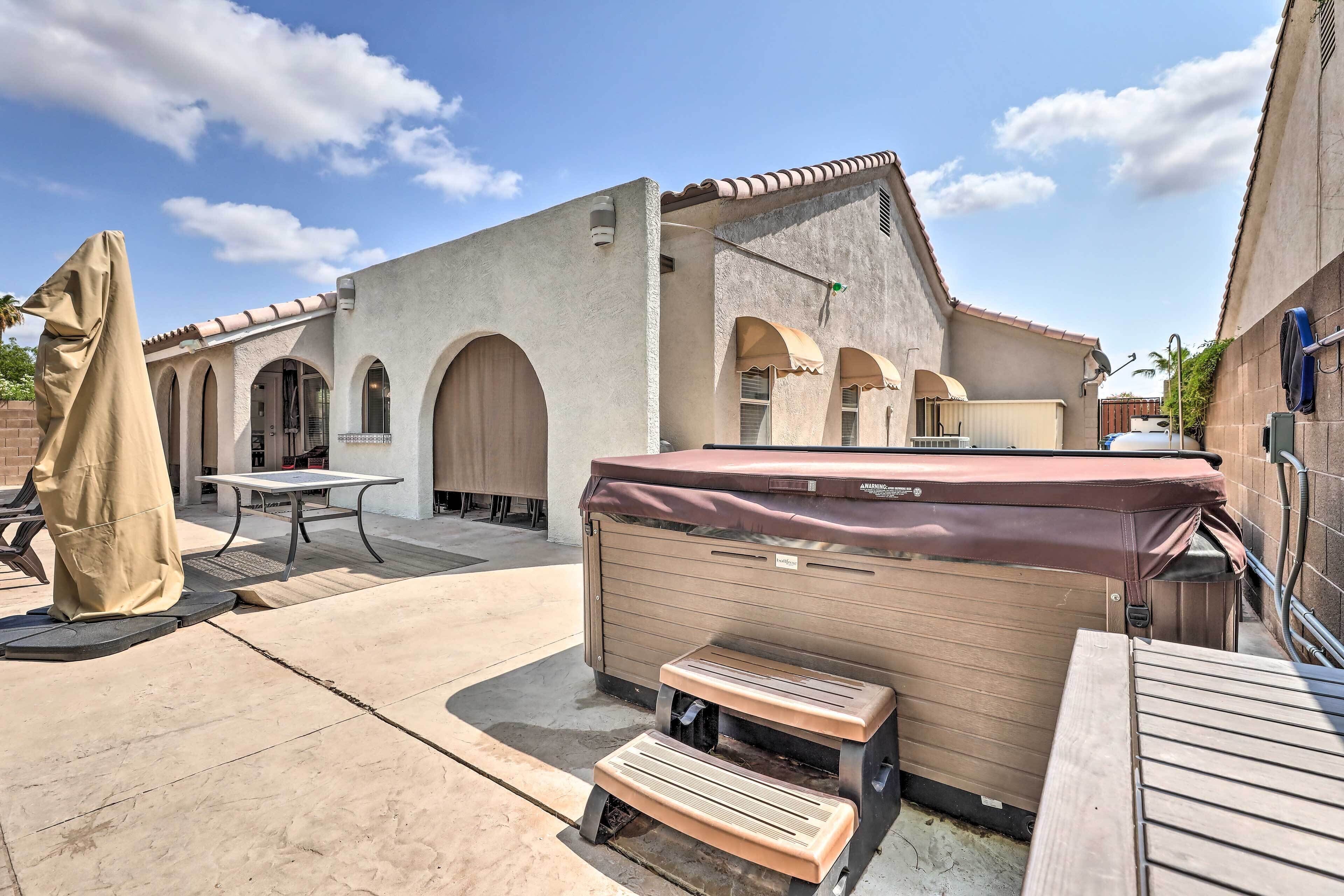 A patio area with a hot tub, a covered table, and a wooden bench.