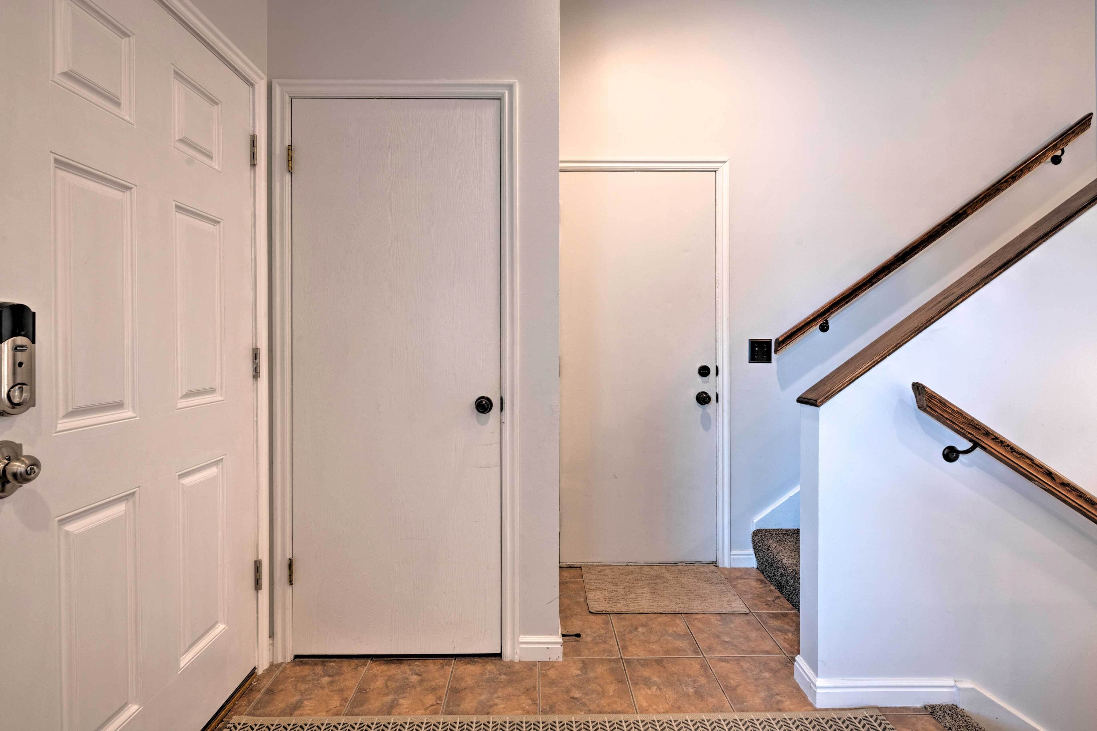 A hallway with white doors, a wooden staircase, and a patterned rug.